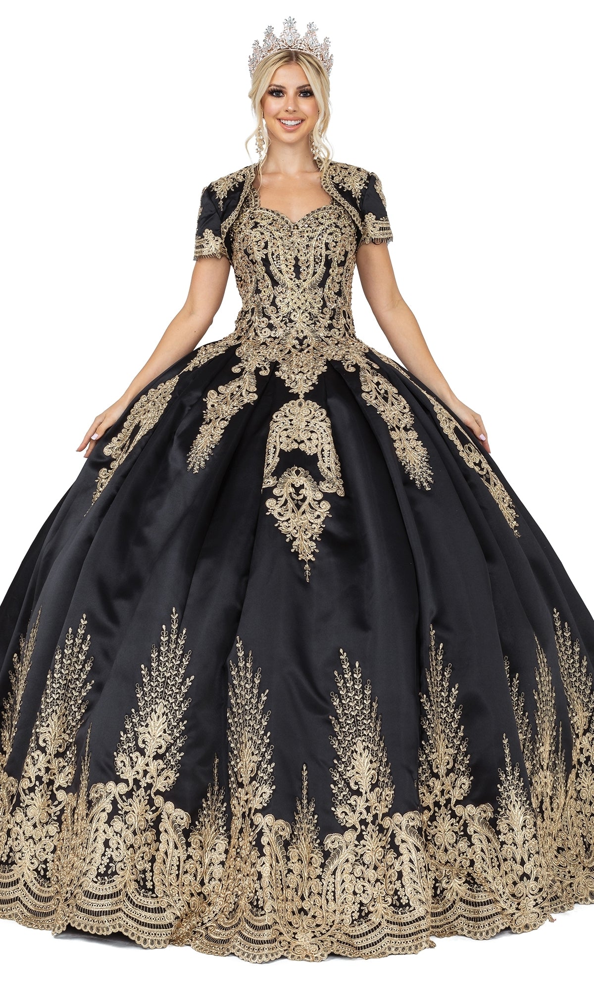 A woman in the Quinceanera Dress 1494 by Dancing Queen, a black a-line ball gown with gold lace embroidery and a matching crown, stands facing forward, holding out the sides of her dress.